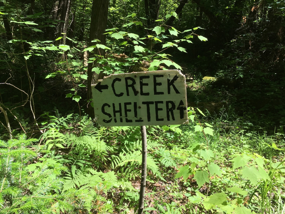 Sign reading "Creek" and "Shelter" with directional arrows