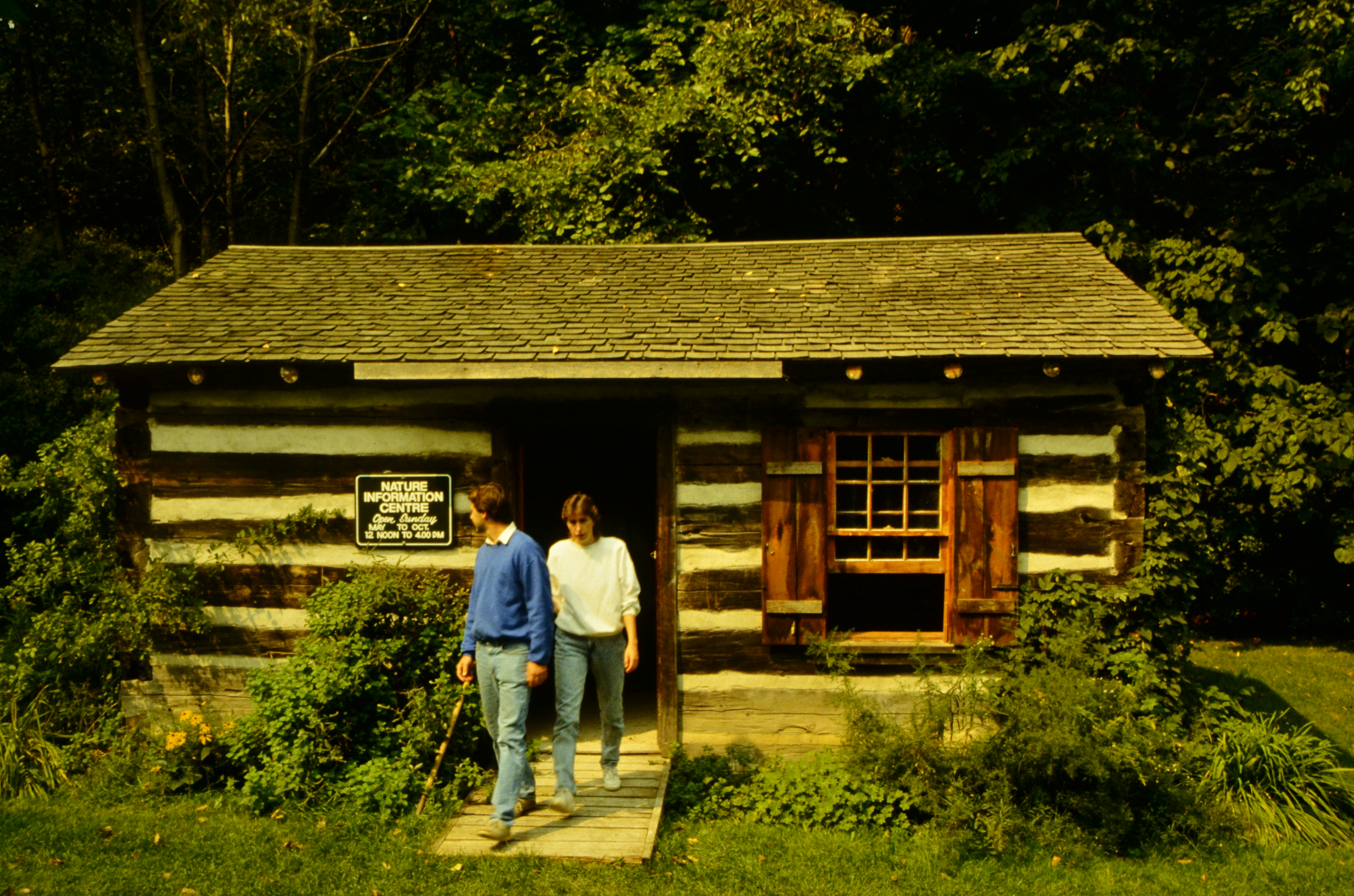 Two people leaving log cabin (Nature Information Centre) in Sunnybrook Park